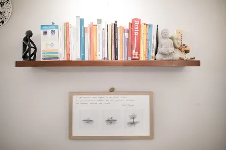Mensola con libri e piccole statue sopra un quadretto