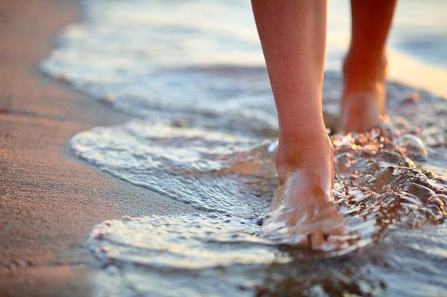 Piedi nudi che camminano sulla sabbia bagnata in riva al mare