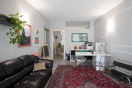 Sala dello studio con divano in pelle, tappeto e scrivania